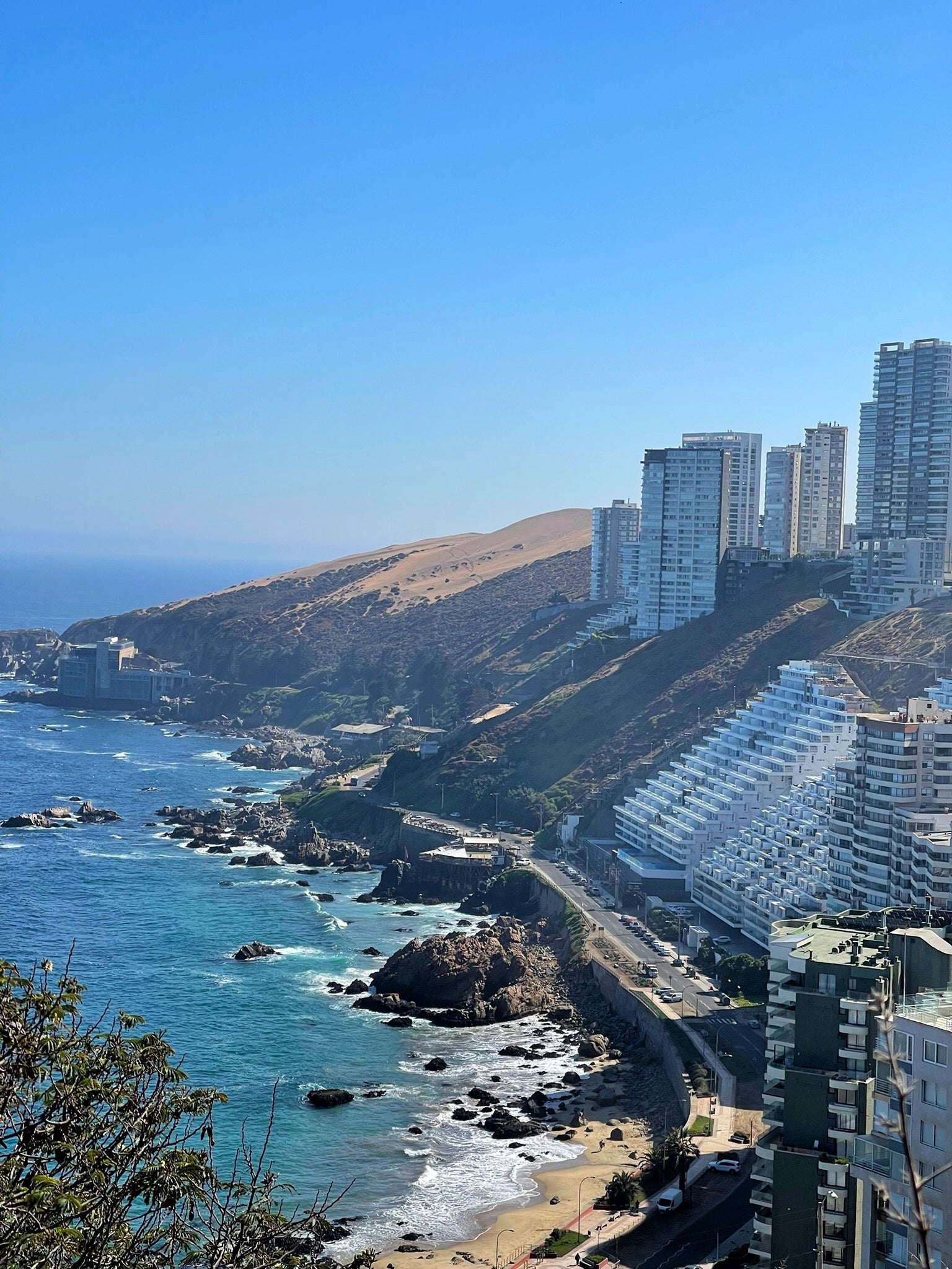 Vista desde un punto elevado hacia Cochoa y las dunas de Concón. Seven los edificios, las dunas y el mar rompiendo en las rocas